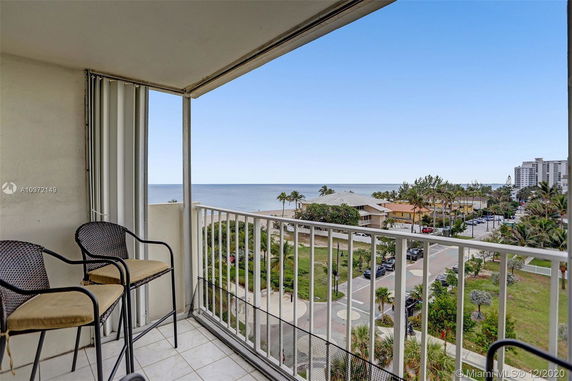 Elevated view from a balcony overlooking a coastal area with ocean and buildings.