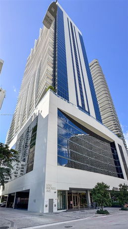Front view of a modern high-rise building with large glass windows and white exterior at 1010 Brickell Ave.