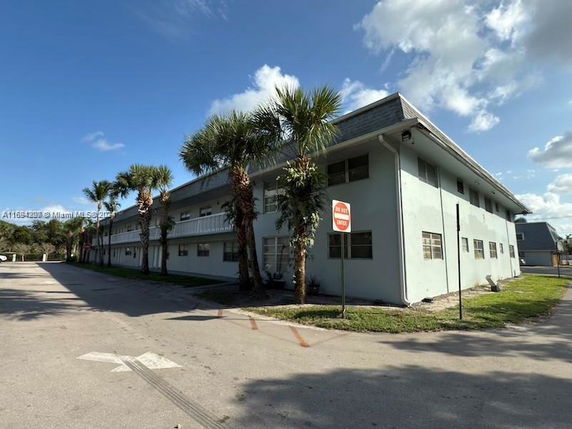 Front view of a two-story building with palm trees.