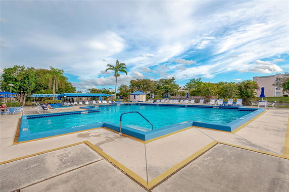 Outdoor swimming pool with adjacent seating area and umbrellas.
