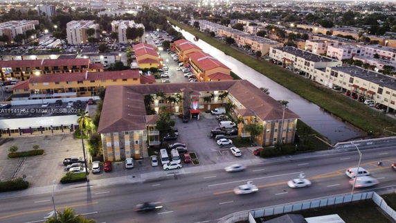 Aerial view of a commercial and residential area with multiple buildings and a road in the foreground.