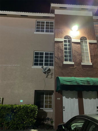 Front view of a multi-story residential building with a satellite dish and green awning.