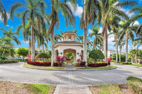 Front view of a small pavilion surrounded by palm trees and landscaped gardens.