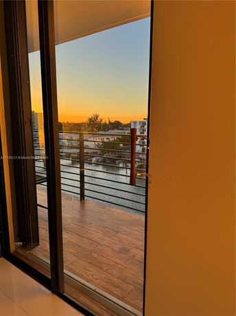 View from a balcony overlooking a waterway and buildings at sunset.
