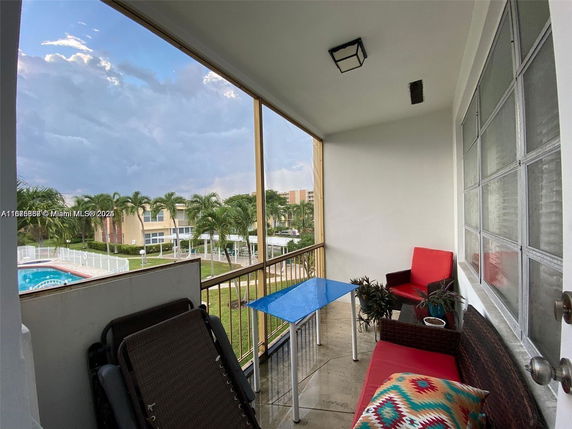 Balcony view showing a swimming pool and surrounding residential buildings with palm trees.