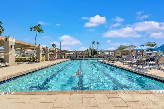 Outdoor swimming pool with lounge chairs and umbrellas surrounding it.