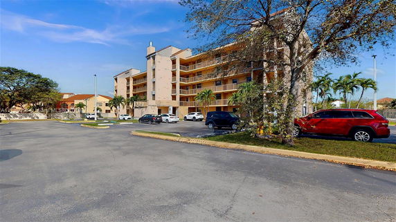 Front view of a multi-story residential building with balconies and parking area.