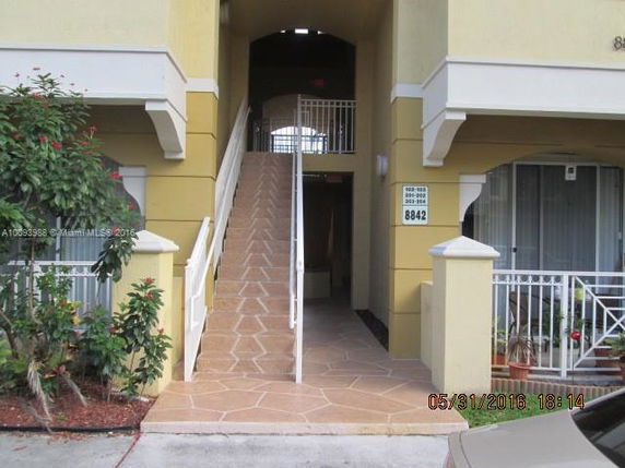 Entrance view of a two-story building with a ramp and railings.