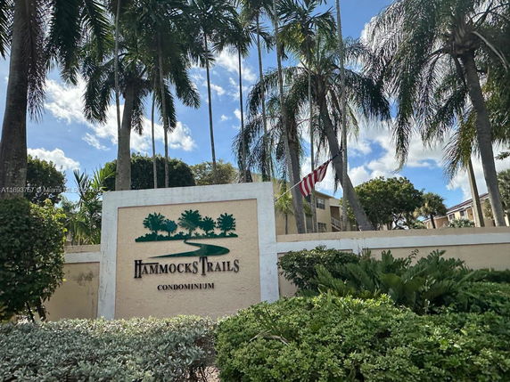 Front view of condominium entrance with a sign for Hammocks Trails.