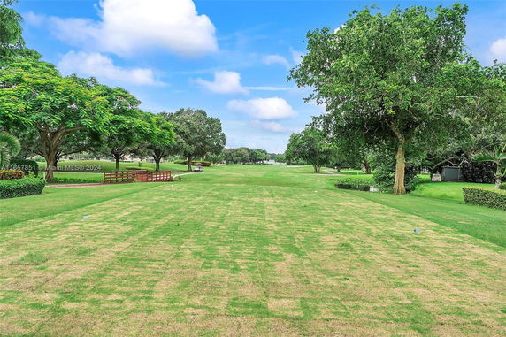 Open green lawn area with trees and blue sky.