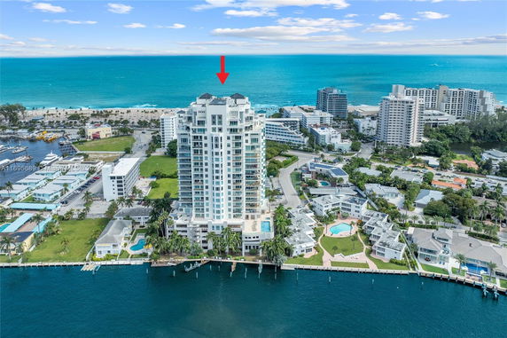 Aerial view of a coastal area with a prominent tall building and ocean backdrop.
