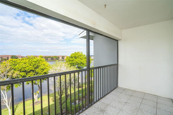 Balcony view overlooking trees and a body of water.