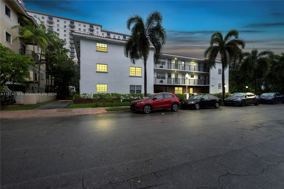 Front view of a multi-story building with exterior corridors and palm trees.