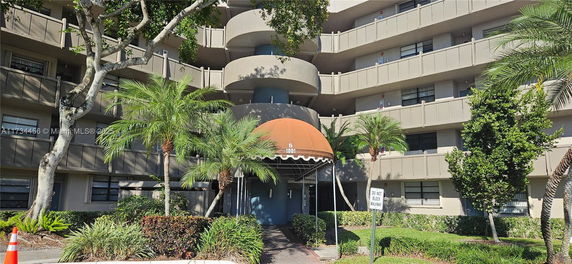 Front view of a multi-story residential building with balconies and an entrance canopy.