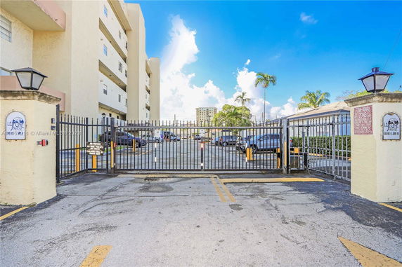 Gated entry to a parking area in front of a multi-story building.