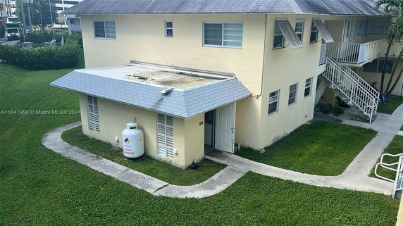 Front view of a two-story house with exterior stairs and propane tank.