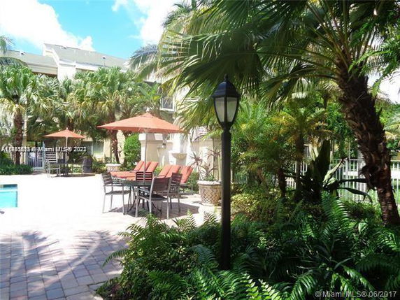 Outdoor seating area next to a swimming pool with palm trees and umbrellas.