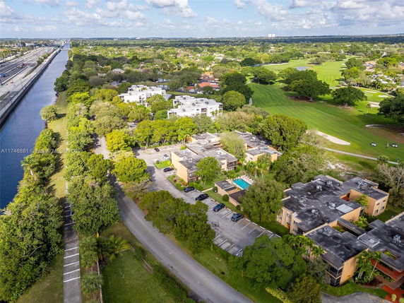 Panoramic view of a residential area with several buildings, a swimming pool, and surrounding greenery.