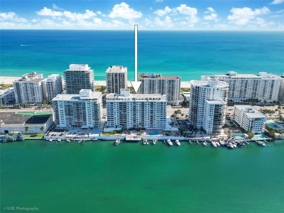 Aerial view of multiple beachfront apartment buildings with a view of the ocean in the background.