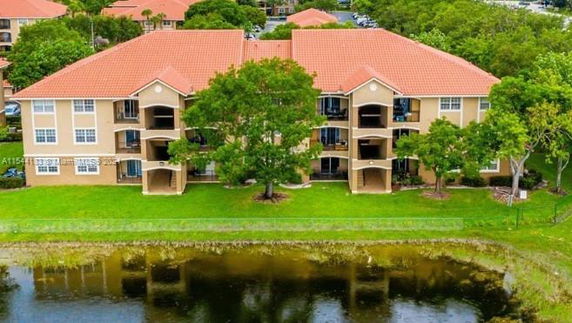 Front view of a three-story building with red-tiled roofs and balconies overlooking a pond.