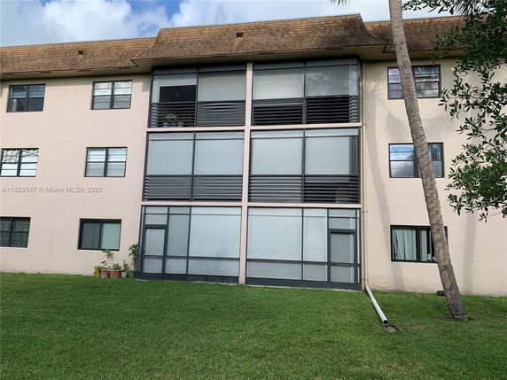 Front view of a multi-story building with large windows and sliding doors.