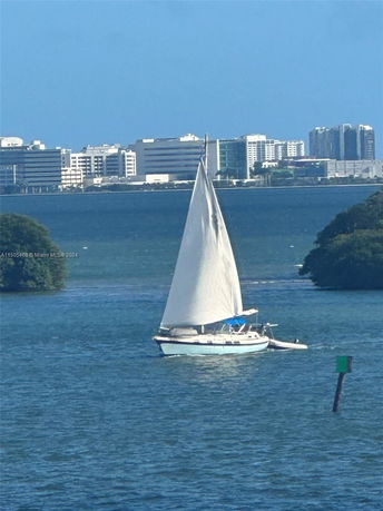View of a sailboat on the water with buildings in the background.
