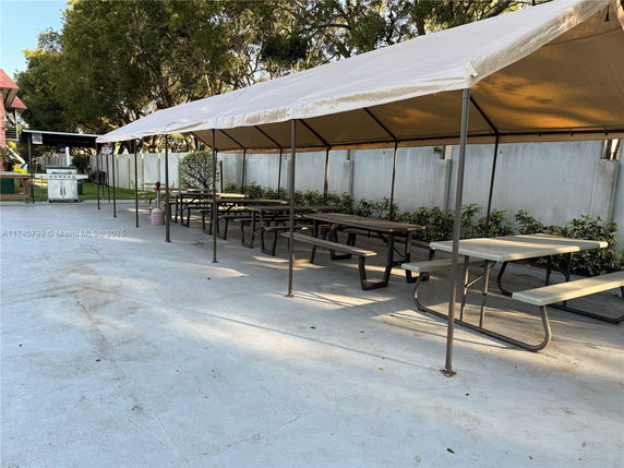 Outdoor area with covered picnic tables and a grill.