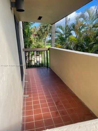 View from a balcony with a tiled floor and railing overlooking greenery.