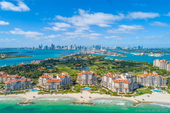Panoramic view of beachfront buildings and distant city skyline.