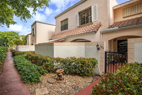 Front view of a two-story townhouse with a tiled roof and gated entrance.