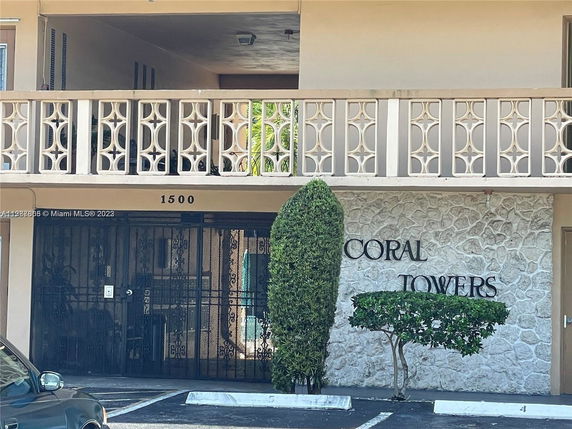 Front view of a building with a stone facade labeled Coral Towers and a decorative balcony railing.