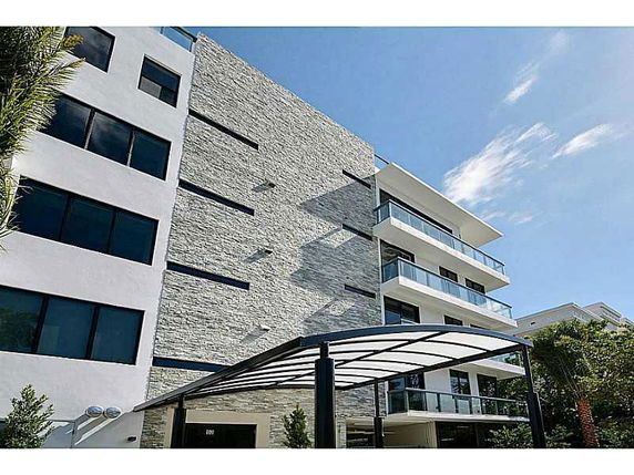 Front view of a modern multi-story building with stone facade and balconies.