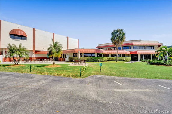Front view of a large building with red awnings and outdoor seating area.