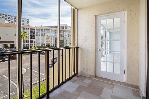 Balcony view overlooking a parking lot and adjacent building with glass windows.