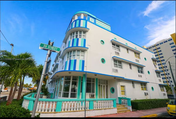 Front view of a multi-story building with a distinctive blue and white facade on a corner street.