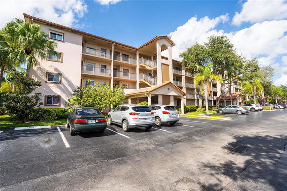 Front view of a multi-story residential building with balconies and associated parking area.