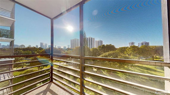 View from a balcony overlooking greenery and distant buildings.