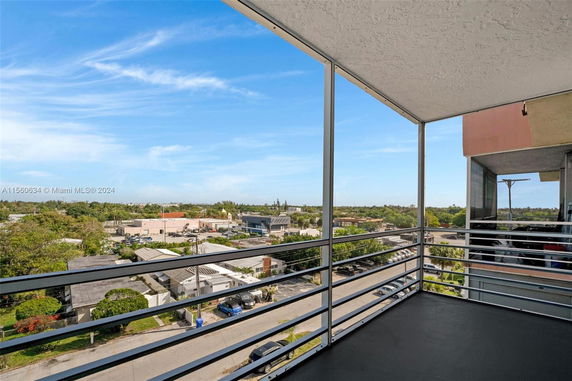 View from a balcony showing an urban landscape with buildings and trees.