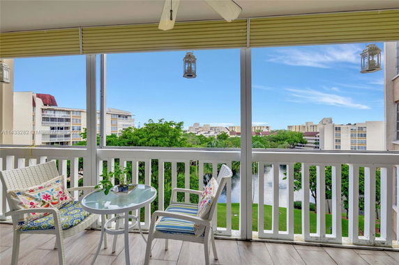 View from a balcony with chairs and a table, overlooking other buildings and greenery.