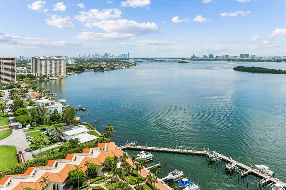 Panoramic view of waterfront cityscape with marina and high-rise buildings.