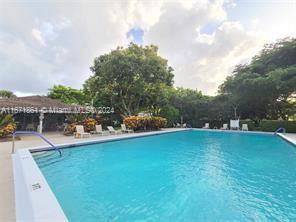 Outdoor swimming pool surrounded by trees and lounging areas.