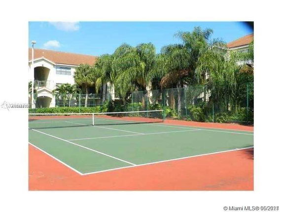 Tennis court with a residential building in the background.