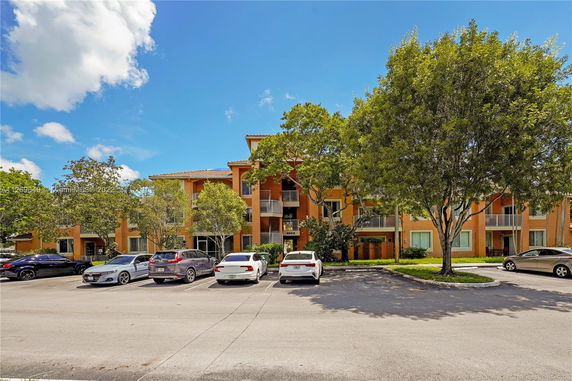 Front view of a multi-story apartment building with a parking area in front.