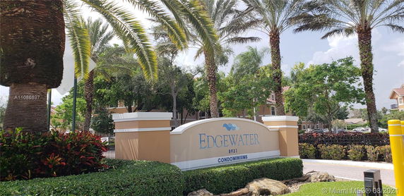 Front view of a condominium with a sign and surrounding palm trees.