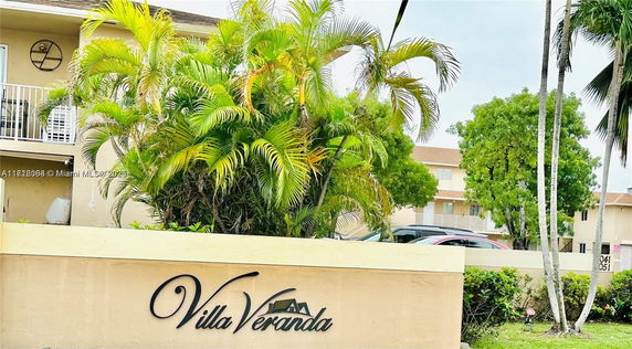 Front view of a residential building with a sign reading 'Villa Veranda' and palm trees.