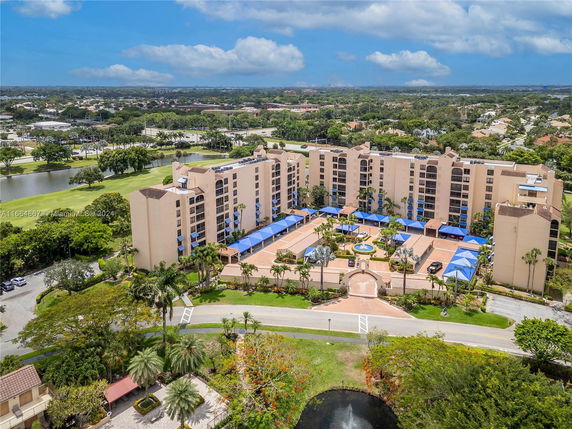 Aerial view of a multi-story residential building complex with a central courtyard and surrounding trees.