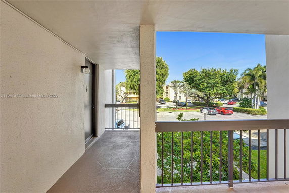 Balcony view of a residential complex and parking lot.