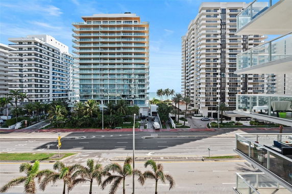 View of multiple high-rise buildings near a road with palm trees.