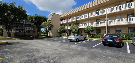 Outdoor parking area in front of a three-story residential building with balconies.