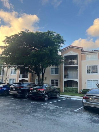 Front view of a multi-story apartment building with balconies and parking area.